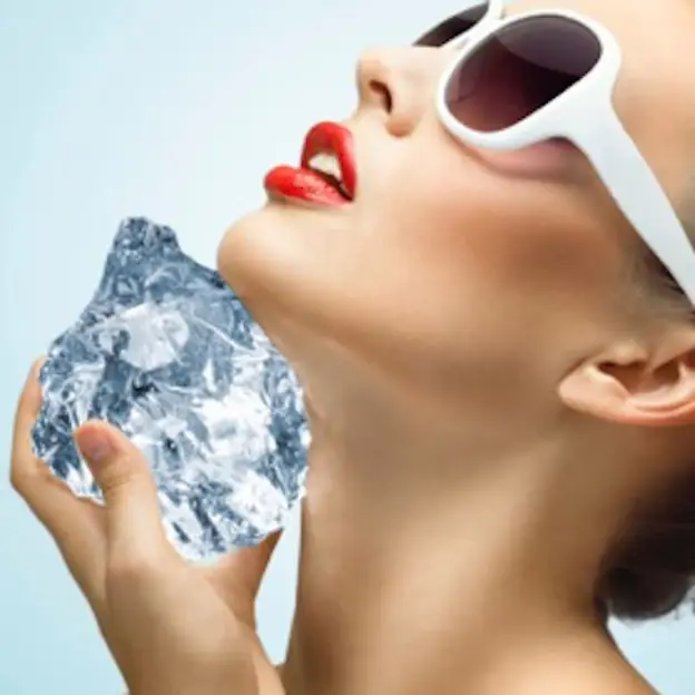 A woman with vibrant red lipstick and stylish white sunglasses holds a large piece of ice woman with red lips and white sunglasses holding an ice chunk